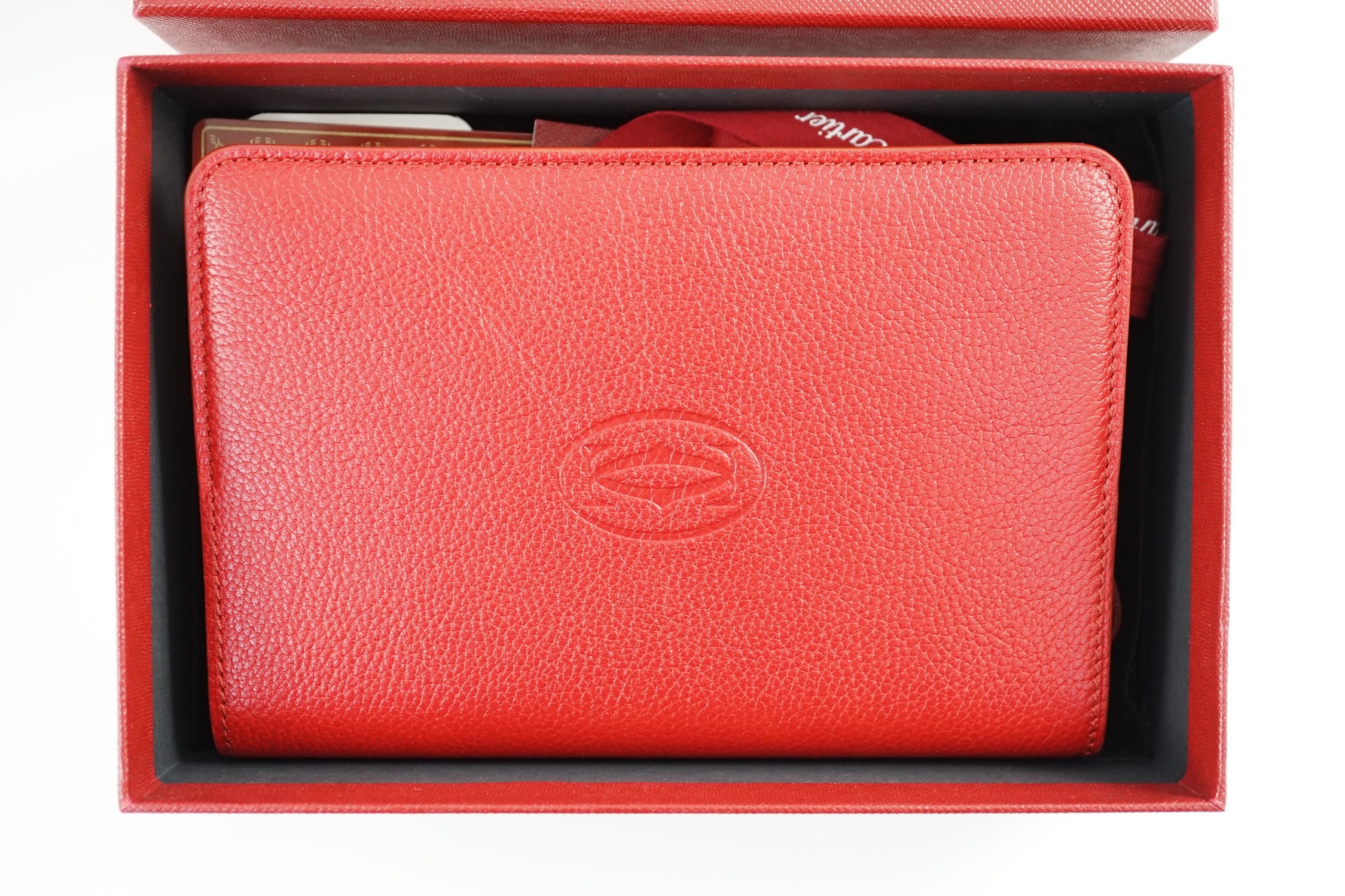 A Cartier red leather notebook, boxed, with bag, papers and certificate